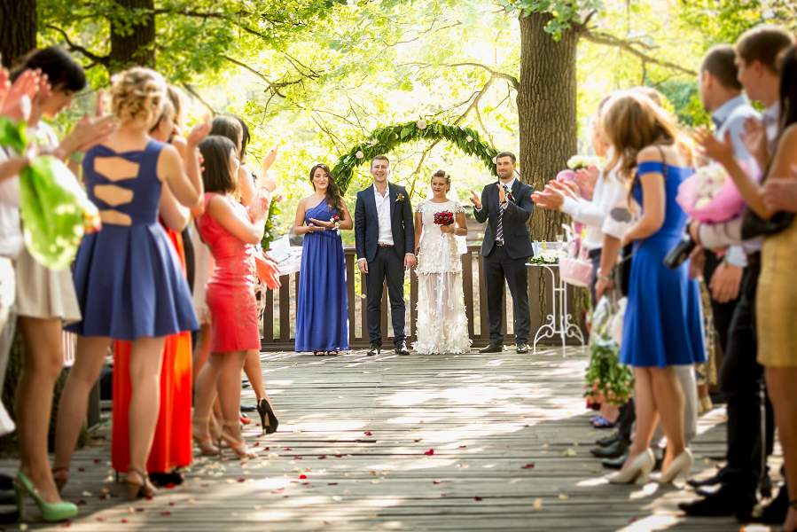 The wedding party and guests gather at a summer outdoor wedding.